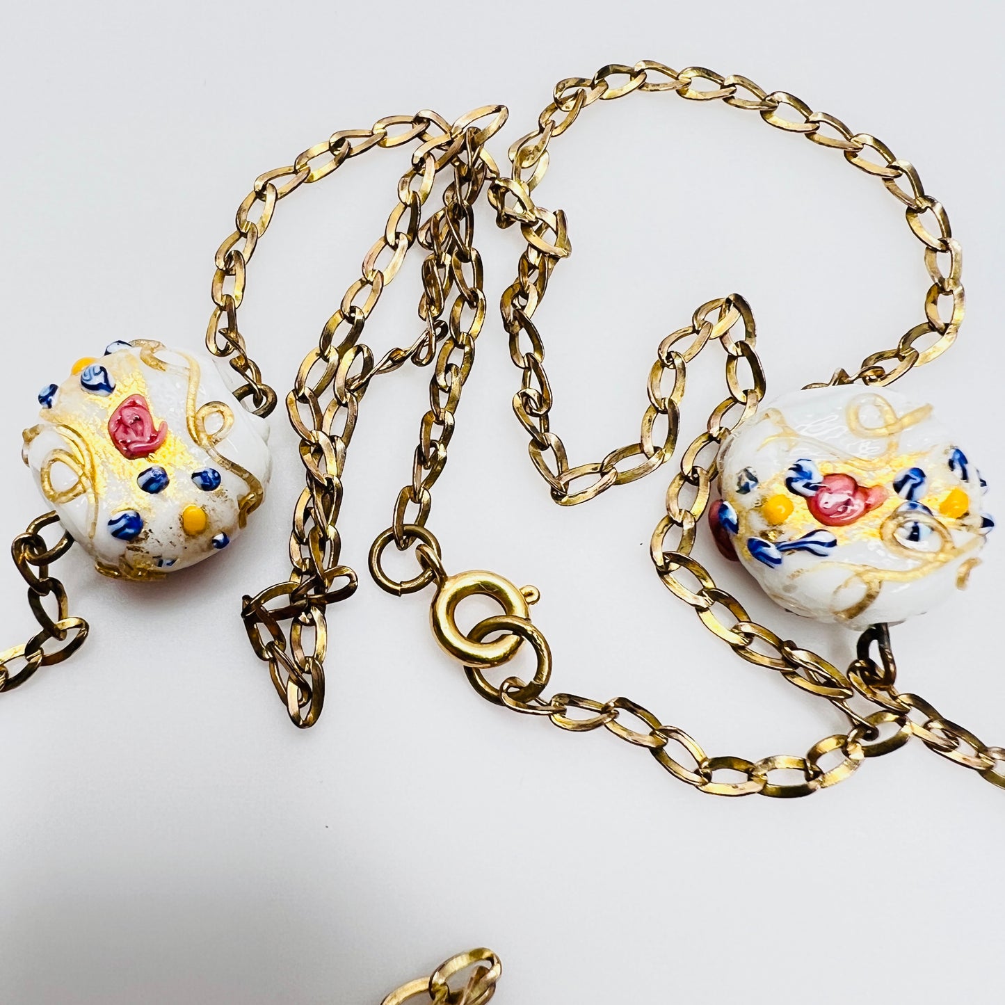Close-up of Venetian wedding cake beads with multicolor floral details and gold chain