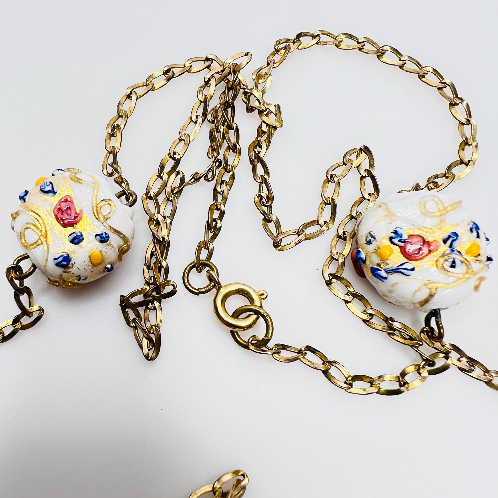 Close-up of Venetian wedding cake beads with multicolor floral details and gold chain