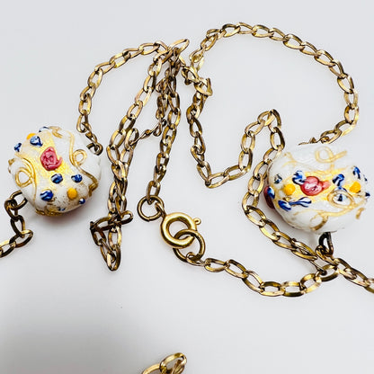 Close-up of Venetian wedding cake beads with multicolor floral details and gold chain
