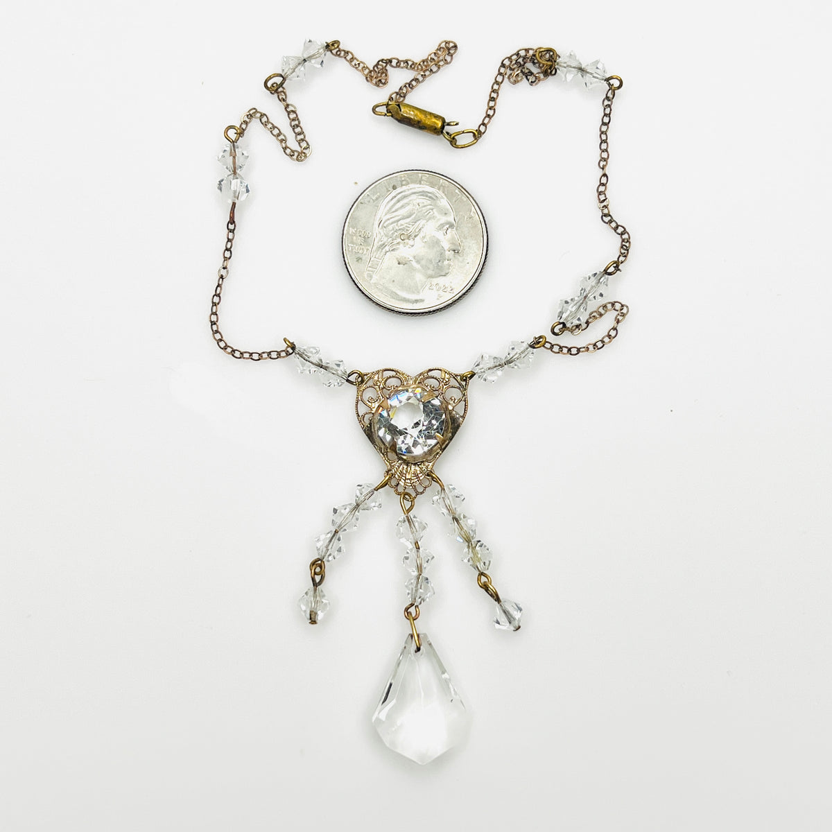 Vintage 1920s crystal necklace with heart filigree pendant shown beside quarter for scale