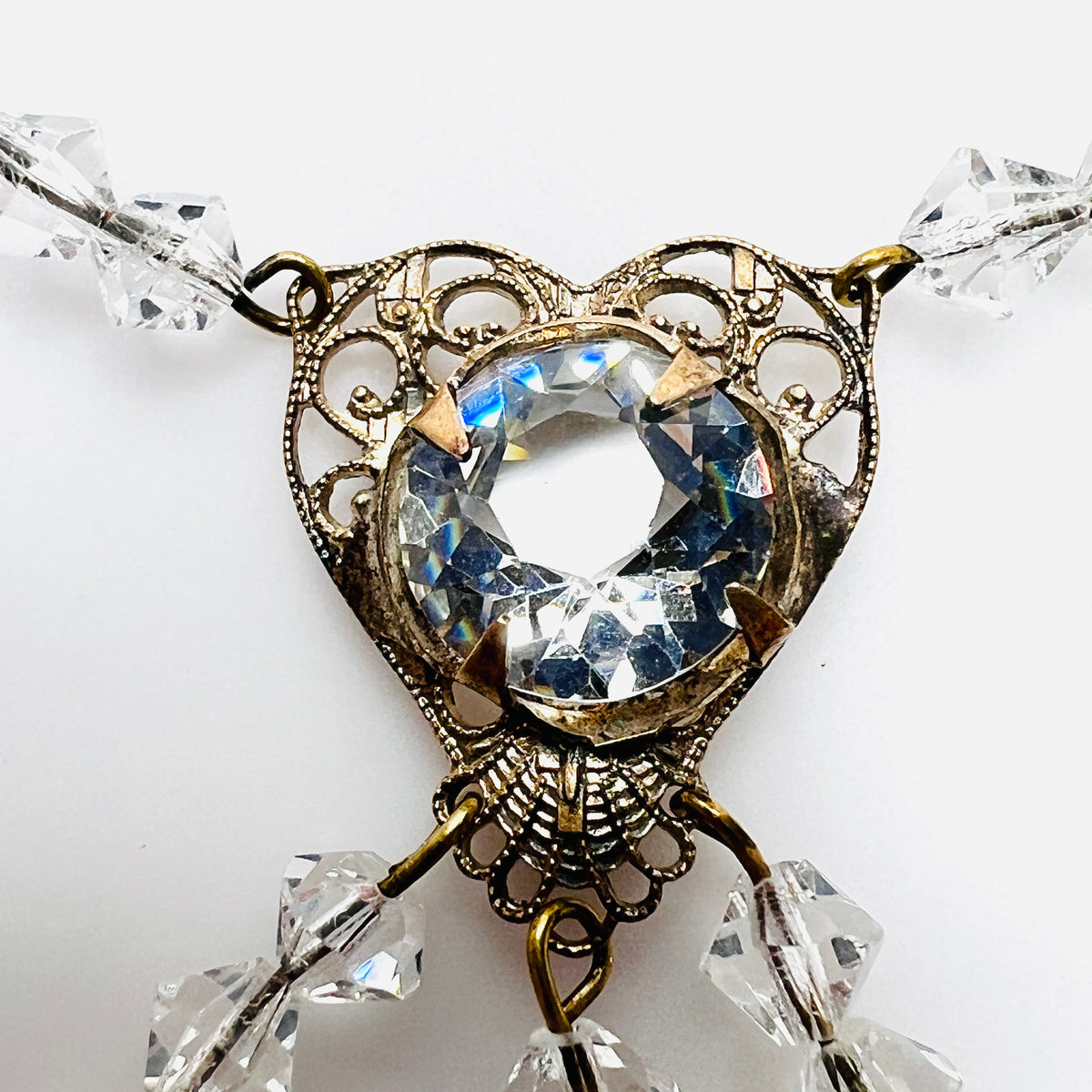 Close-up of ornate filigree heart necklace with large round faceted clear crystal
