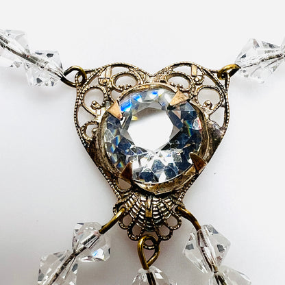 Close-up of ornate filigree heart necklace with large round faceted clear crystal