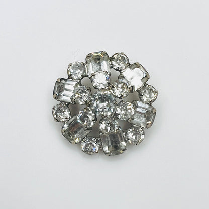 Vintage 1950s signed Weiss clear rhinestone brooch with round and emerald-cut glass crystals in a silver-tone circular cluster setting.
