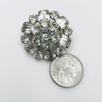 Vintage Weiss crystal brooch beside a quarter for size comparison, showing sparkling clear prong-set rhinestones.