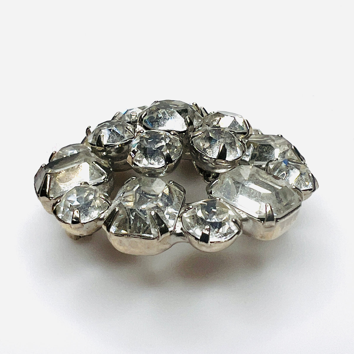 Side view of vintage Weiss rhinestone brooch showing raised silver-tone settings and dimensional crystal cluster construction.