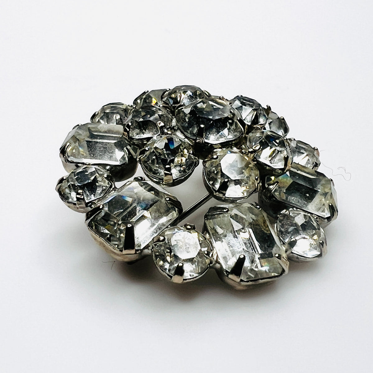 Side view of vintage Weiss rhinestone brooch showing raised silver-tone settings and dimensional crystal cluster construction.