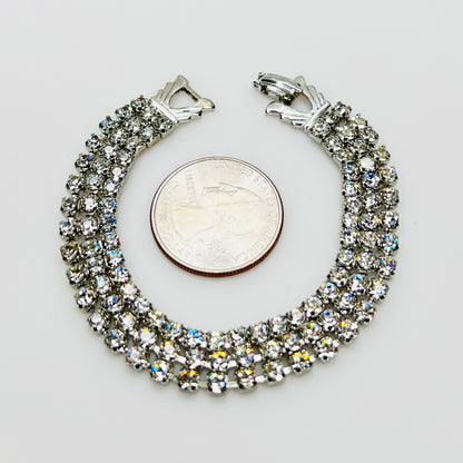 Triple strand Weiss crystal bracelet with silver tone setting beside quarter for scale